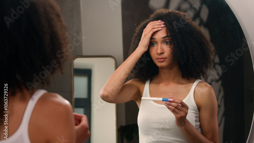 Worried scary afraid anxious African American woman girl in bathroom looking on positive pregnant test shocked unwanted pregnancy unplanned motherhood pregnant problem sad upset female holding head photo
