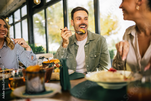 Group of happy friends eating lunch together in a restaurant. They eat delicious salads, hamburgers, bread and meat. photo