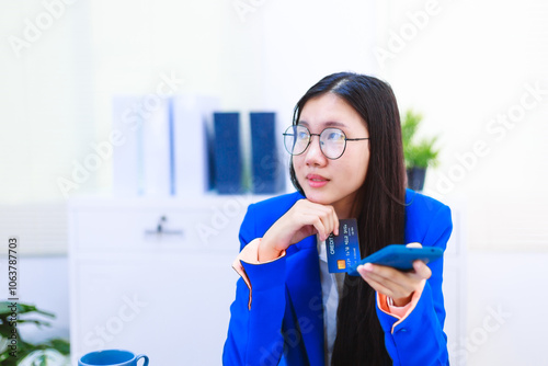 An Asian woman sits at her desk, surrounded by files , embodying dedication and professionalism in her work.