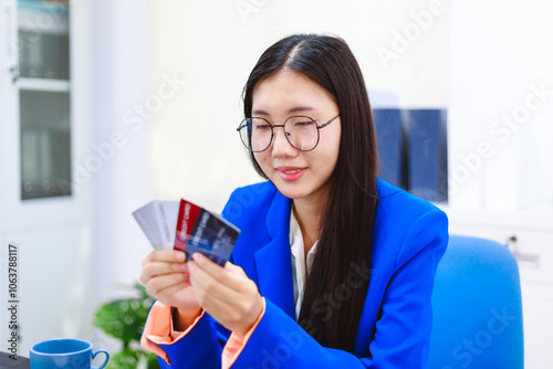 An Asian woman sits at her desk, surrounded by files , embodying dedication and professionalism in her work.