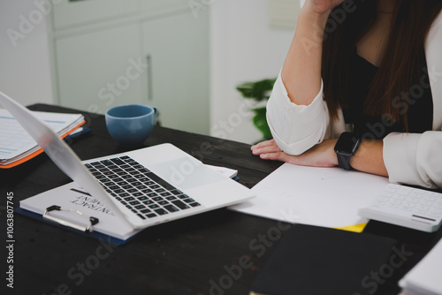 Asian businesswoman, focused , sits at ablack wooden table. Surrounded by notes , she strategizes her next move, embodying confidence and professionalism in her workspace. photo