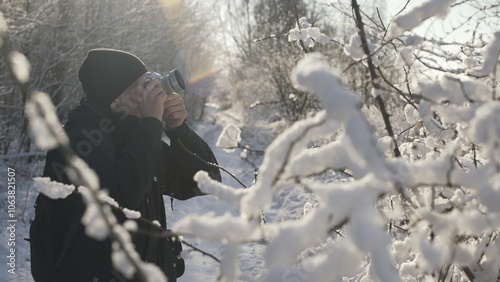 A young man taking pictures in the winter forest.