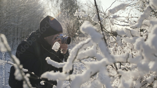A young man taking pictures in the winter forest.