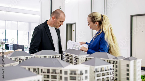 A real estate manager in the office shows the layout of the apartment and advises the client on purchase, rental and mortgage issues. Concept of buying or renting real estate. photo