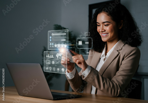 A woman engages with digital technology while working on her laptop in a modern office setting during the daytime