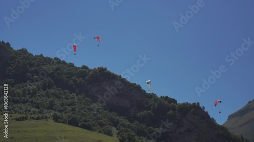 Paragliding Sky Mountains - Paragliders soar over a mountain range on a clear day.