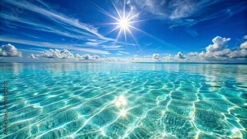 A tranquil, crystal-clear ocean water background, with gentle ripples and sunlight streaming through the surface, creating shimmering reflections on the white sand below photo