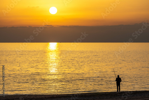 Fototapeta Naklejka Na Ścianę i Meble -  Lonely fisherman on the beach at sunset. Side, Manavgat, Antalya, Turkey