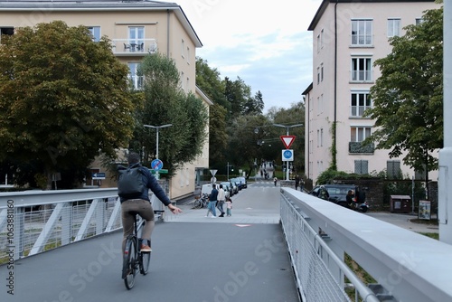 Salzburg, Austria - October 1 2024: Cyclist Gesturing with Hand to Signal Turning to the Right While Riding on Urban Bridge