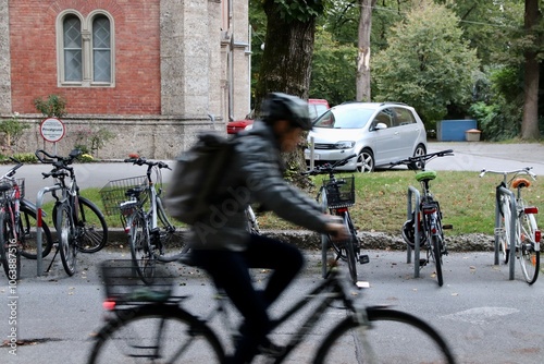 Salzburg, Austria. Blurred Cyclist Riding Past Parked Bicycles on a Quiet Street in a European Neighborhood