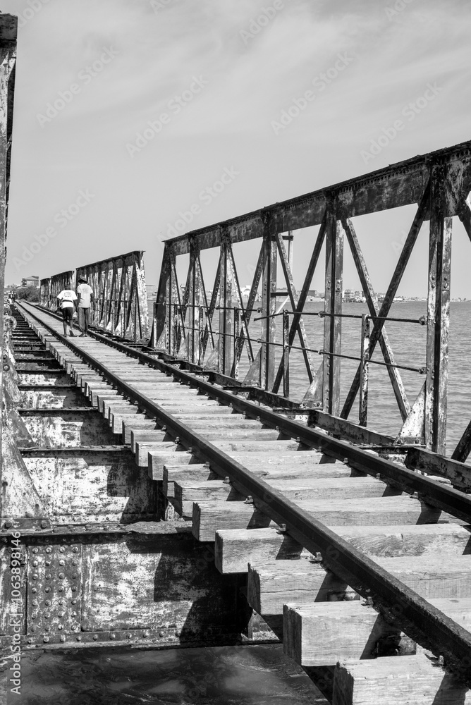 Fototapeta premium Un pont de chemin de fer traverse une rivière dans la ville de Saint Louis du Sénégal en Afrique de l'Ouest
