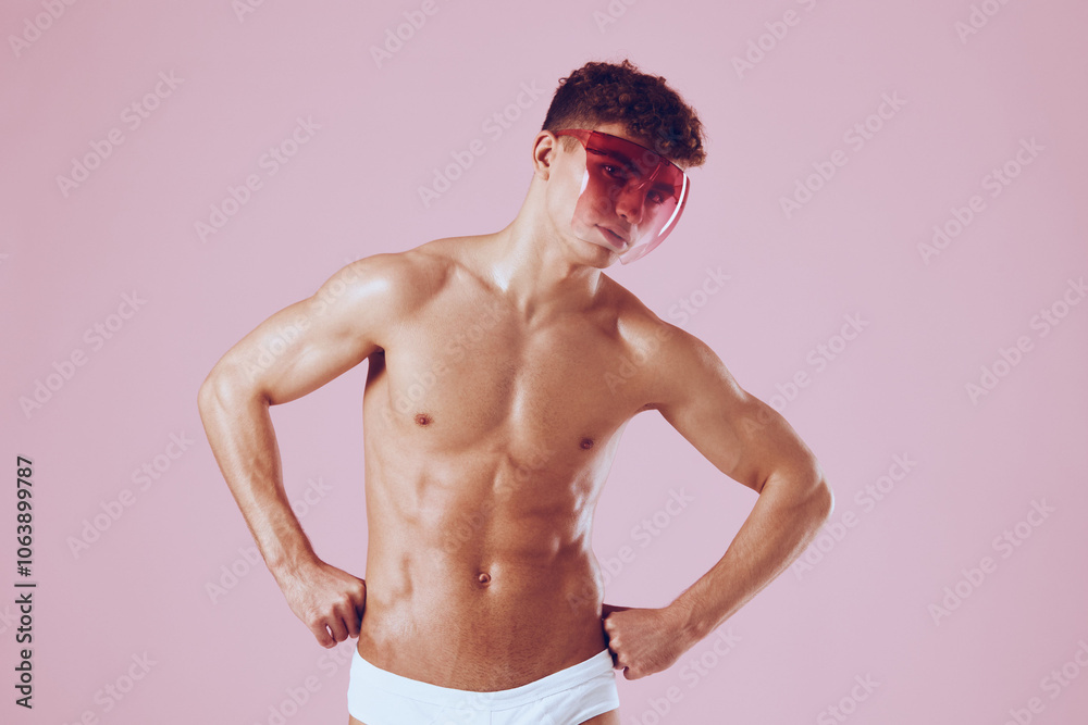 Fototapeta premium Confident young man posing with pink background, wearing only white briefs and stylish sunglasses. Fashion and summer vibes concept.