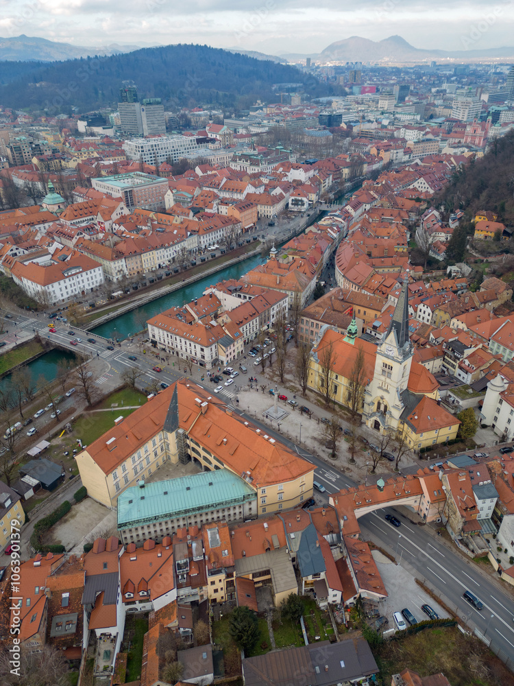 Ljubljana old town above Karlovška cesta road with Church of St. James. Aerial vertical view of the capital city of Slovenia in the winter. Roznik hill and Smarna Gora at distance. Ljubljana old town above Karlovška cesta road with Church of St. James. Aerial vertical view of the capital city of Slovenia in the winter. Roznik hill and Smarna Gora at distance.