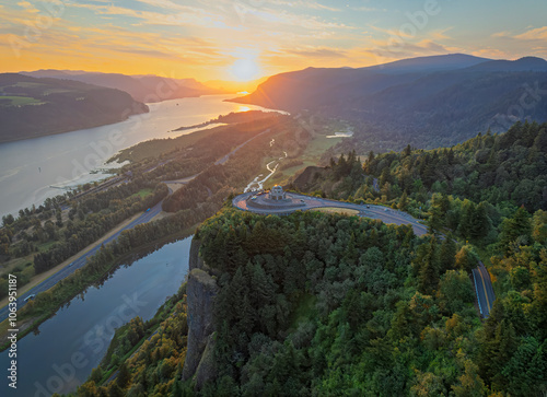 A breathtaking aerial view of at sunrise illuminating Vista House at Crown Point, the Columbia River Gorge and lush forest, highlighting a serene morning in nature. photo