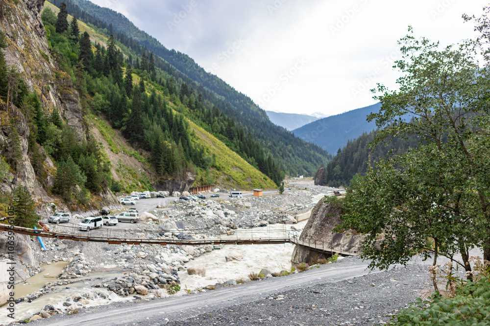 MESTIA GEORGIA - AUGUST 22, 2024: Chalaadi glacier bridge and parking for tourists car and buses.