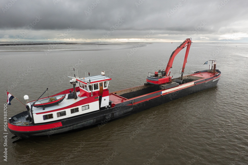 Red dredging vessel working on sea, removing sediment in a waterway Red dredging vessel working on sea, removing sediment in a waterway