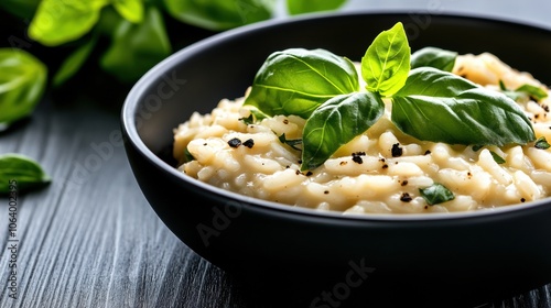 Creamy risotto garnished with fresh basil leaves in a black bowl, AI