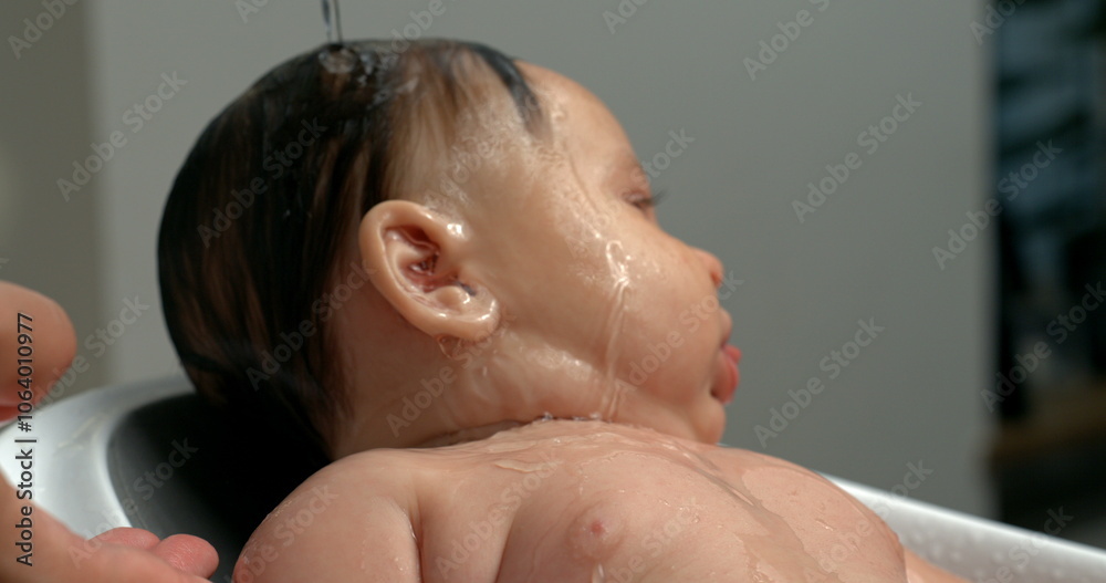 Close-up of a baby having water poured over the head during bath time, slow motion at 800 fps, gentle and calming bath routine, intimate moment of care Close-up of a baby having water poured over the head during bath time, slow motion at 800 fps, gentle and calming bath routine, intimate moment of care
