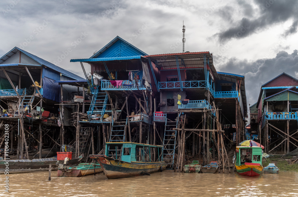 The colorful village of Kampong Phluk with houses on stilts, fishing boat and fishing nets near Siem Reap in Cambodia The colorful village of Kampong Phluk with houses on stilts, fishing boat and fishing nets near Siem Reap in Cambodia