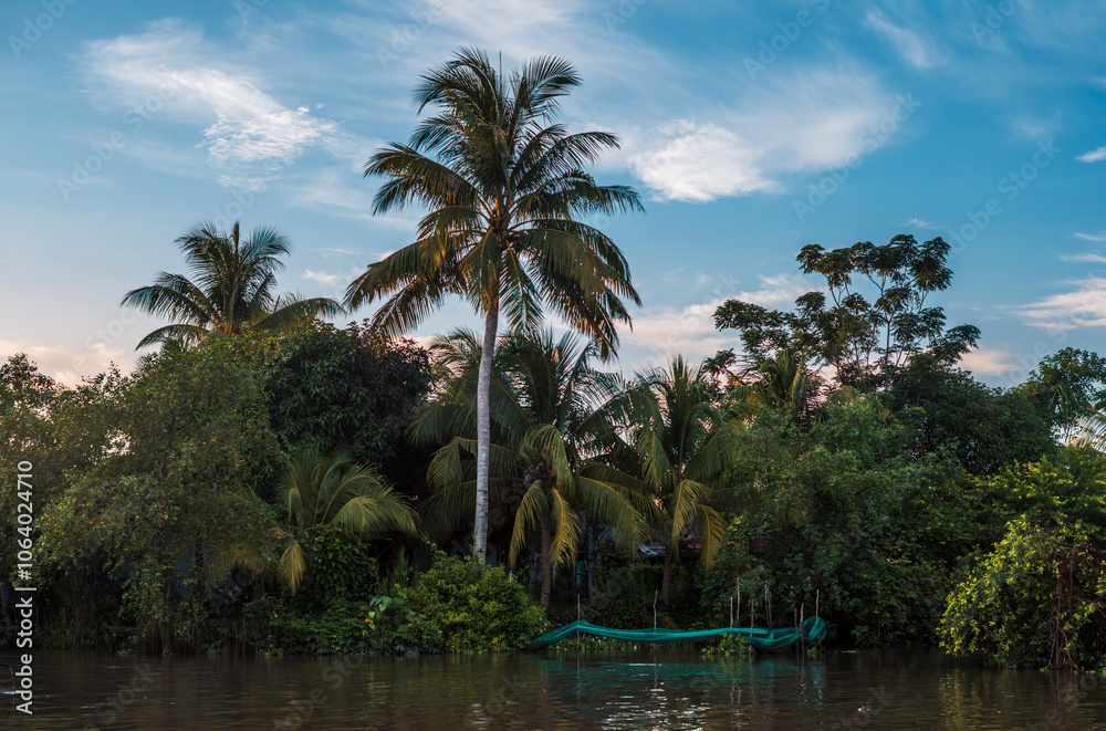 Palm trees, boats and buildings reflecting on the quiet waters of the canals in Can Tho in Vietnam Palm trees, boats and buildings reflecting on the quiet waters of the canals in Can Tho in Vietnam