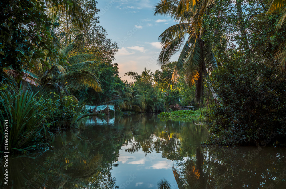 Palm trees, boats and buildings reflecting on the quiet waters of the canals in Can Tho in Vietnam Palm trees, boats and buildings reflecting on the quiet waters of the canals in Can Tho in Vietnam