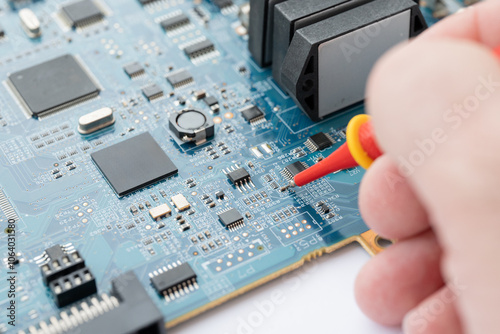 Technician testing electronic circuit board with probe
