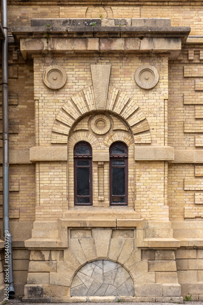 Fototapeta premium Windows and decoration details of a yellow brick wall, vintage building facade