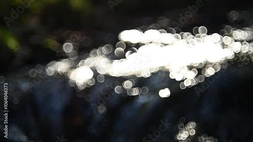Bokeh shot of a mountain stream in an autumn forest, sunlight effects, slow motion, camera movement