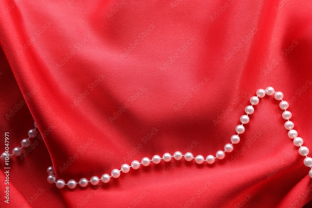 Beautiful pearl necklace on red cloth, top view. Space for text Beautiful pearl necklace on red cloth, top view. Space for text
