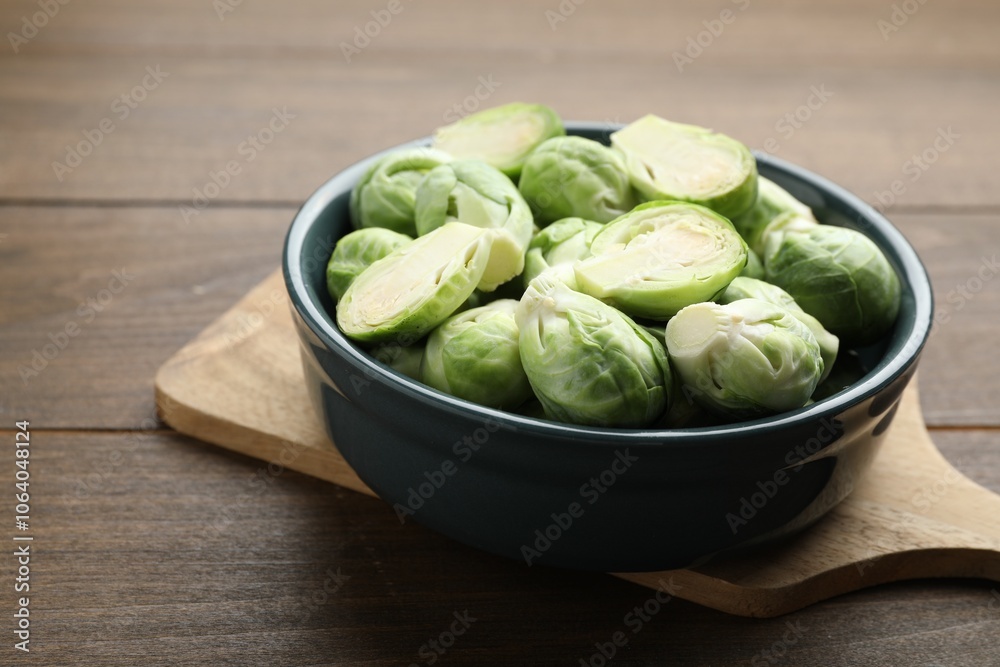 Fresh green Brussels sprouts in bowl on wooden table, closeup