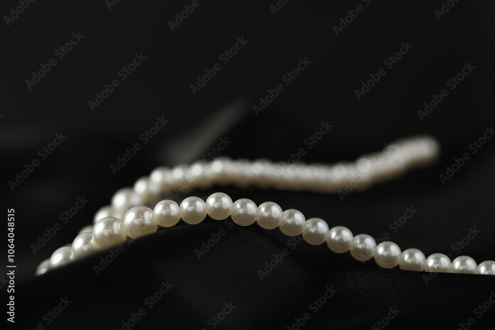 Beautiful pearl necklace on black silk, closeup