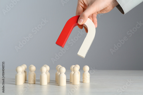 Fotografie Woman with magnet attracting wooden human figures at light table, closeup