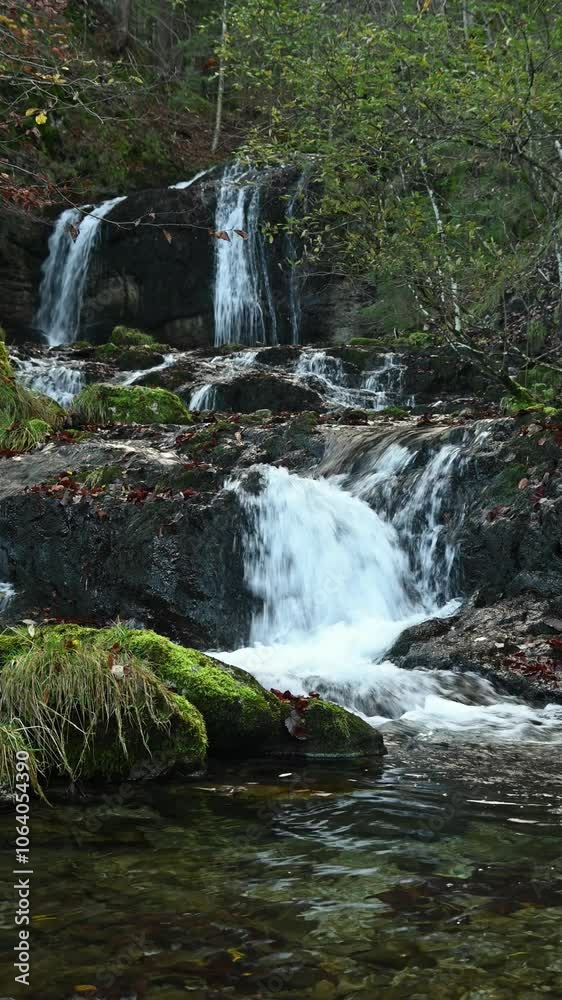 Vertical shot of cascading waterfalls in an autumn forest Vertical shot of cascading waterfalls in an autumn forest