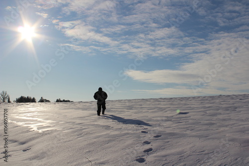 The figure of a man walks through the winter desert, a man walks upward through the snow photo