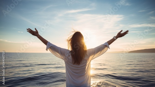 A woman stands by the sea, arms open wide, embracing the sunset's glow with a joyful spirit, epitomizing freedom and boundless happiness. photo