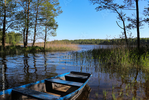 Fototapeta Naklejka Na Ścianę i Meble -  A blue wooden boat moored on the shore of a lake, Borki, Warmian-Masurian Voivodeship, Poland
