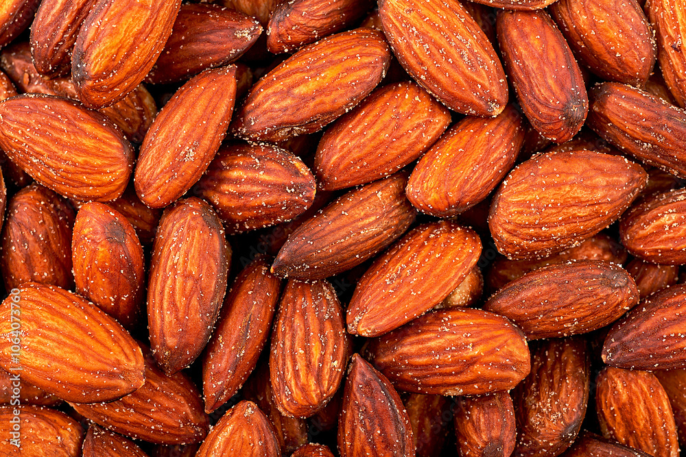 Fototapeta premium Salted and roasted almond nuts as background, top view.