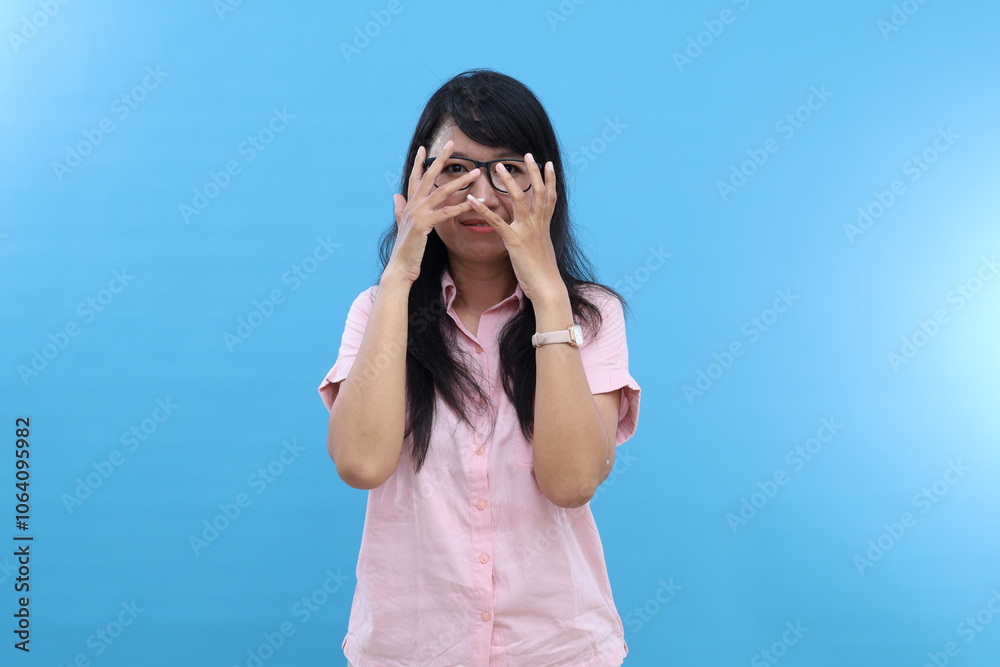Photo of serious carefree relaxed young Asian woman with natural dark hair keeps hand in face looks determined directly at camera wears shirt isolated blue background going to have walk. Photo of serious carefree relaxed young Asian woman with natural dark hair keeps hand in face looks determined directly at camera wears shirt isolated blue background going to have walk.