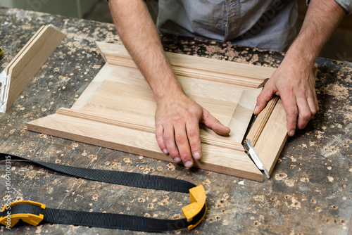 The carpenter glues together the parts of the panel