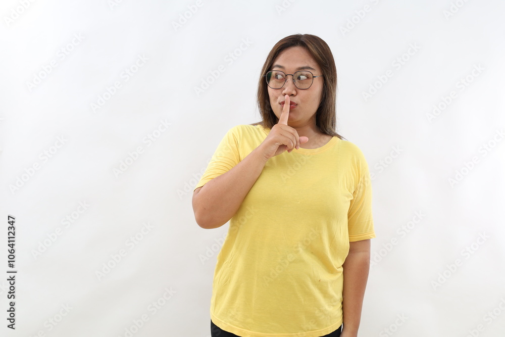 Mysterious Asian woman makes silence gesture shares secret looks aside isolated on white background. Hush be quiet Mysterious Asian woman makes silence gesture shares secret looks aside isolated on white background. Hush be quiet