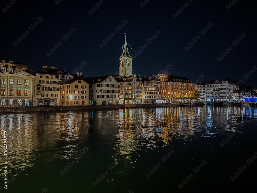 Naklejka premium Beautiful aerial view of the city of Zurich in Switzerland at night - the Limmat River and its iconic churches, buildings rivers and Clocks.
