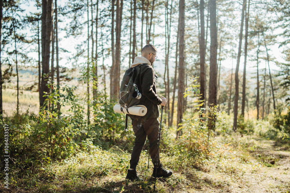 Young caucasian man hiking or trekking through the forest Young caucasian man hiking or trekking through the forest
