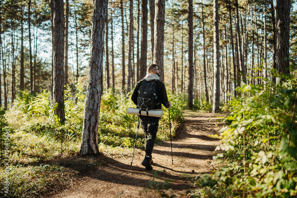 Obraz premium Young caucasian man hiking or trekking through the forest 