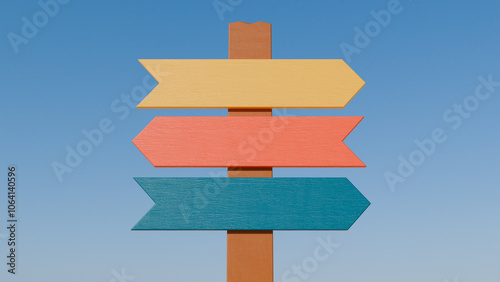 A rustic wooden sign with three colorful arrows pointing in different directions against a blue sky. It symbolizes the multiple options and decisions that life presents us with.