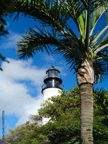 The historic, old and beautiful Key West Lighthouse framed by a tropical coconut palm tree against a perfect blue sky photo