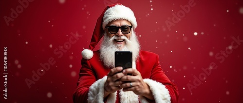 Cheerful Santa Claus wearing sunglasses uses a smartphone against a festive red background, conveying modernity, joy, and holiday spirit. Ideal for Christmas-themed promotions and digital greetings.

 photo