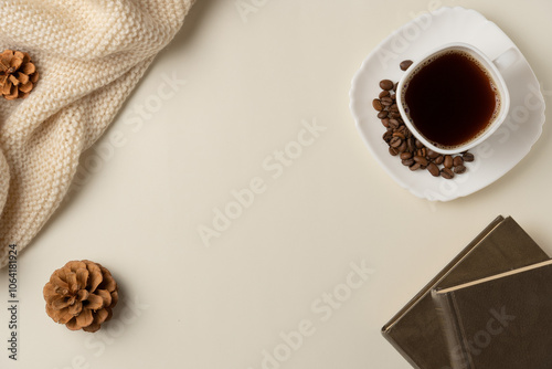 Cup of coffee with coffee beans, books and scarf on beige background. Copy space. Flat lay, top view