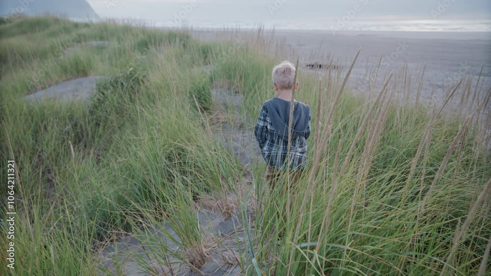 Small child walking through tall grass toward beach - epic slow motion Small child walking through tall grass toward beach - epic slow motion