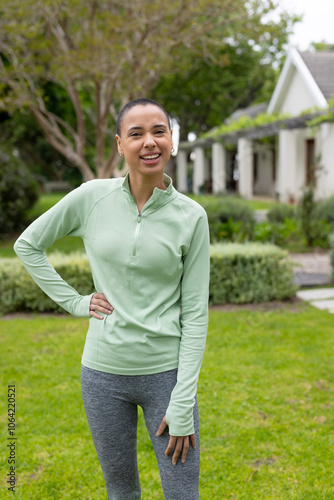 Smiling woman in activewear enjoying outdoor exercise in lush garden