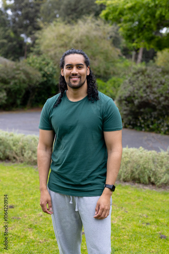 Smiling man standing in park wearing casual clothes, enjoying outdoor greenery